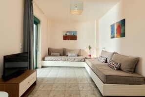 A living room with a sofa, television, and artwork on the wall. - Bella Vista Hotel Apartments (Hersonissos)