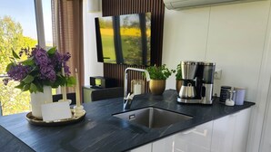 Une cuisine moderne avec un plan de travail noir, des meubles blancs, une machine à café et une plante en pot.