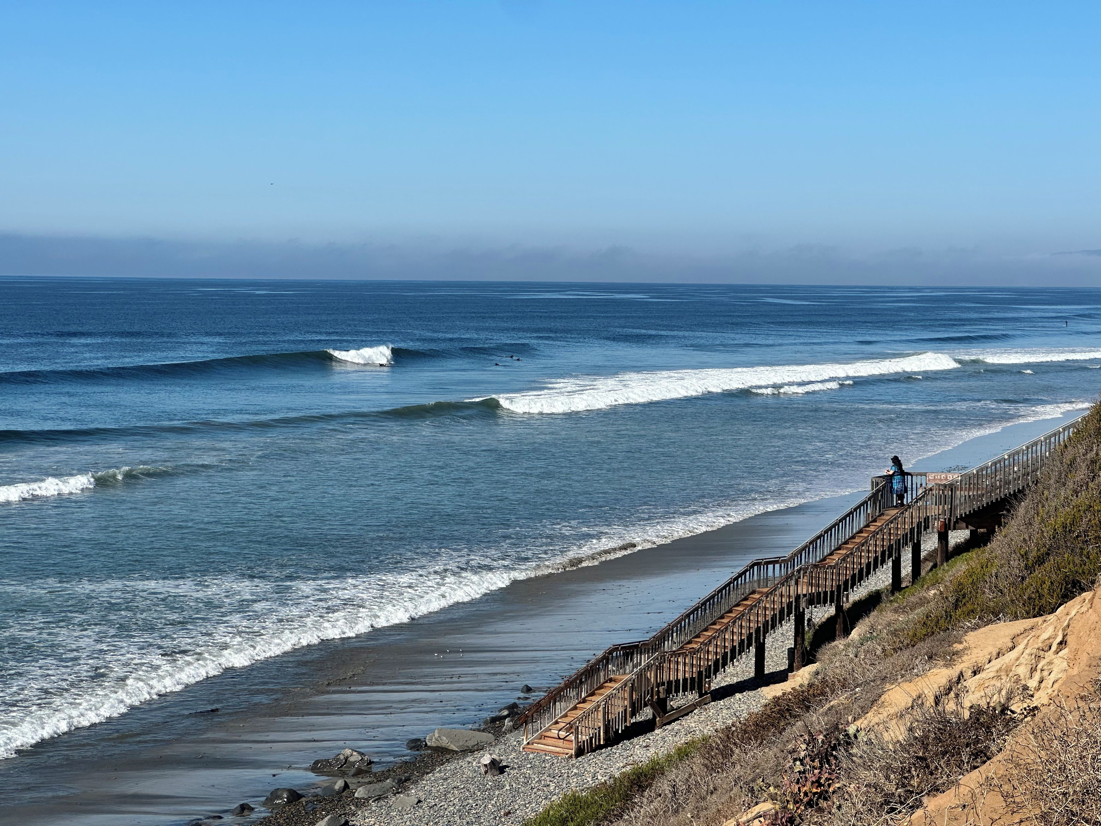 A wooden staircase leading down to a beach with waves.