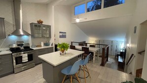 Una cucina moderna con isola centrale, zona pranzo e vista sull'esterno attraverso una finestra.