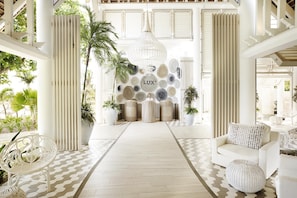 A modern interior with a central wall decorated with various textured objects, a white sofa, and a patterned floor. - LUX Grand Gaube Resort and Villa (Grand Gaube)