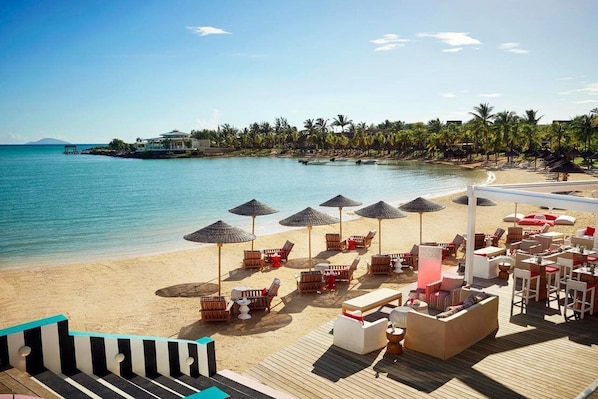 A beach resort with a wooden deck, lounge chairs, umbrellas, and a view of the ocean. - LUX Grand Gaube Resort and Villa (Grand Gaube)