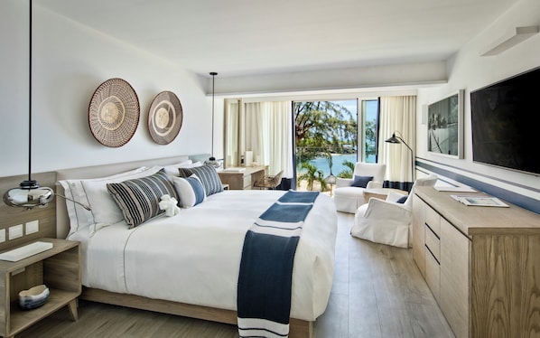 A modern hotel room with a large bed, a desk, and a view of the ocean. - LUX Grand Gaube Resort and Villa (Grand Gaube)