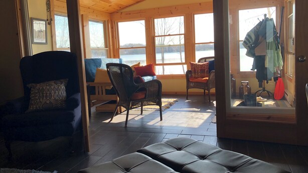 Ein gemütliches Blockhaus-Interieur mit Holzbalkendecke, einer Couch, einem Sessel und einer Bank.