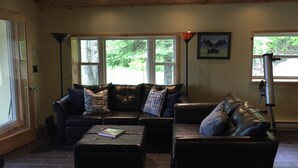 Ein Wohnzimmer mit Ledersofa, Hocker und einem Teleskop.