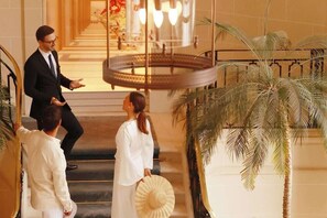 A grand staircase with a palm tree and a decorative railing. - Hotel Du Louvre (Paris)