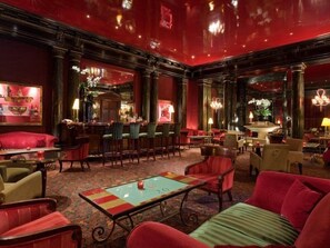 A spacious lobby with a bar area, multiple seating options, and a decorative fountain. - Hotel Du Louvre (Paris)