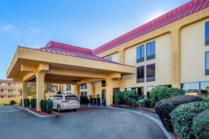 A hotel with a covered entrance, a parking lot, and a building with a red roof. - LA Quinta INN AND Suites BY Wyndham Oakland Airport Coliseum (Oakland)