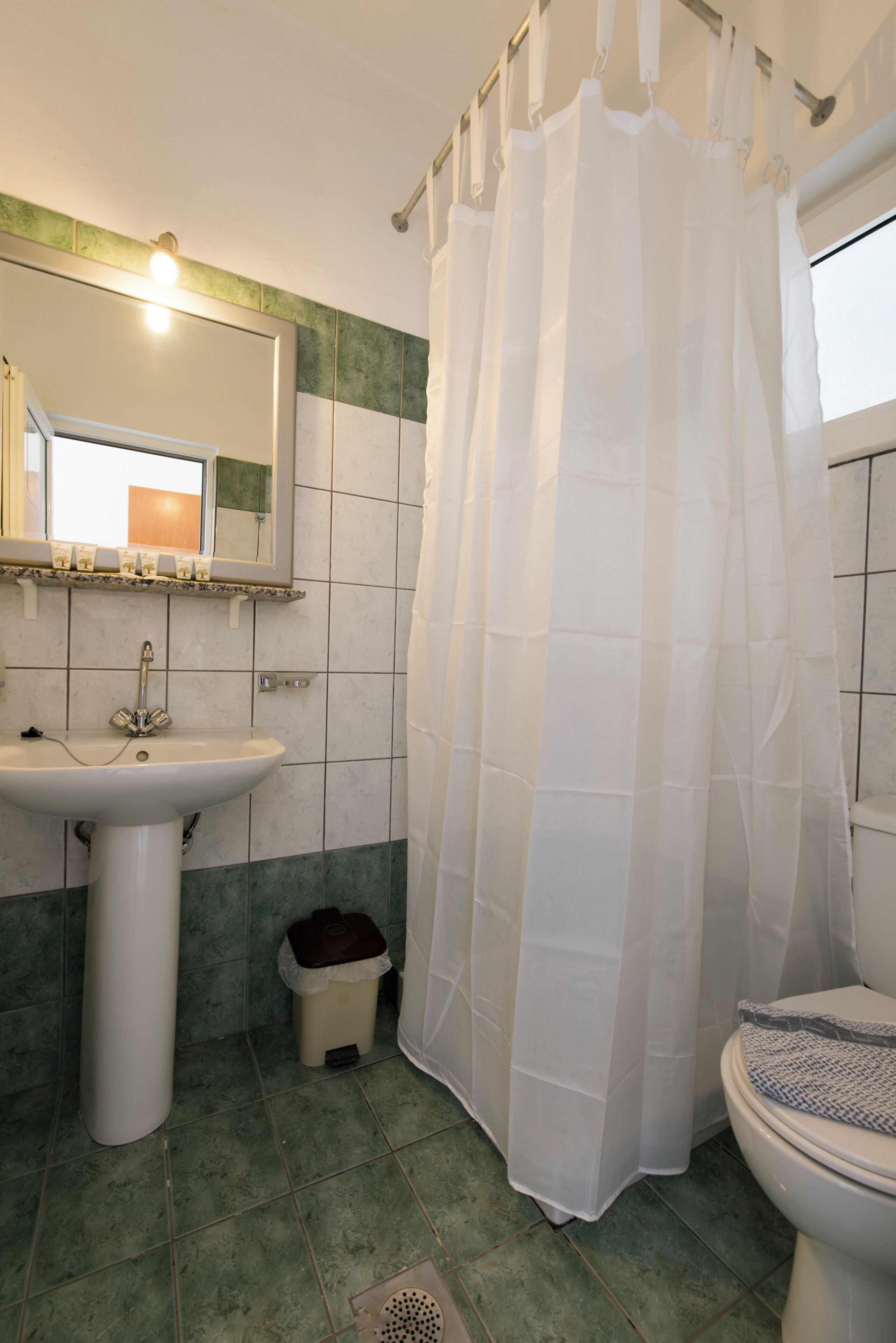 A bathroom with a white sink, a mirror, a toilet, and a shower curtain.