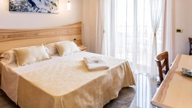 A hotel room with a bed, a dining table, and a painting on the wall. - Santa Chiara Hotel Residence (Ricadi)