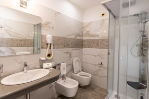 Une salle de bain équipée d’un lavabo, d’un bidet, de toilettes et d’une douche à parois en verre.