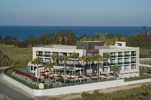Un hotel moderno con zona de piscina, asientos exteriores y vista al océano.