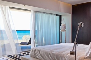 A modern hotel room with a large bed, a view of the sea, a chair, and a hanging light fixture. - Aqua Blu Boutique Hotel and Spa - Adults Only (Kos)