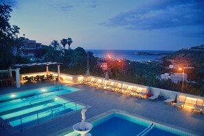 Un espace piscine comprenant plusieurs piscines, des chaises longues et une vue sur la mer.