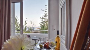 A balcony with a table set for two, featuring a bottle of wine, glasses, and fruit. - Bali Mare (Mylopotamos)
