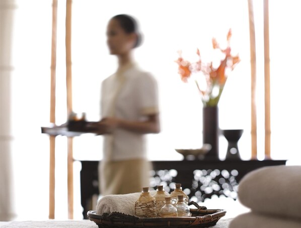 A room with a wicker basket containing bottles, a vase with flowers, and a person standing in the background. - Makati Shangri-la (Makati)