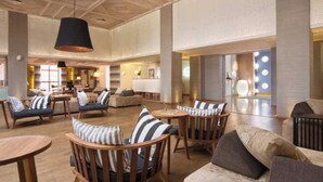 Un hall d’entrée spacieux avec de hauts plafonds, des meubles en bois et un lustre moderne.