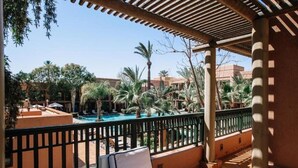 Un espace aménagé au bord de la piscine, offrant une vue sur la piscine, les palmiers et un coin salon abrité.