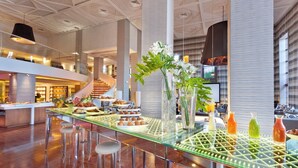 Un hall d’hôtel moderne avec une table à manger en verre, des tabourets de bar et un escalier.