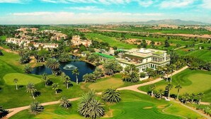 Un terrain de golf avec un grand bâtiment et un étang.