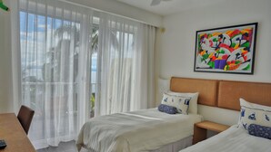 A hotel room with two beds, a dining table, and a large window with sheer curtains. - Xeliter Vista Mare (Samaná)