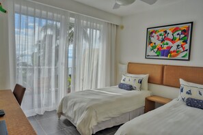 A hotel room with two beds, a dining table, and a large window with sheer curtains. - Xeliter Vista Mare (Samaná)