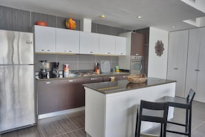 Una cocina moderna con una isla central, electrodomésticos de acero inoxidable y un comedor con sillas.