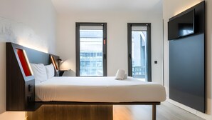 A modern hotel room with a bed, bedside tables, a flat-screen TV, and large windows. - Madrid Centro Atocha (Madrid)