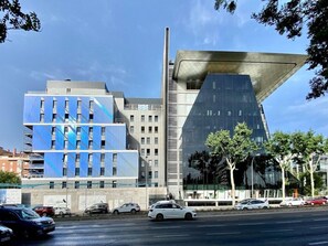 A modern building with a unique angular design, a parking lot, and a clear sky. - Madrid Centro Atocha (Madrid)