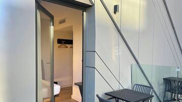 Een modern interieur met een glazen scheidingswand, een tafel met stoelen en een hangende kapstok.
