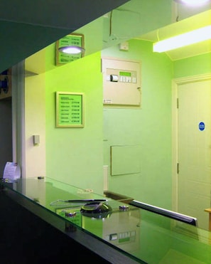 A room with a glass partition, a door with a blue sign, and a wall-mounted device. - Best Western Kensington Olympia Hotel (London)