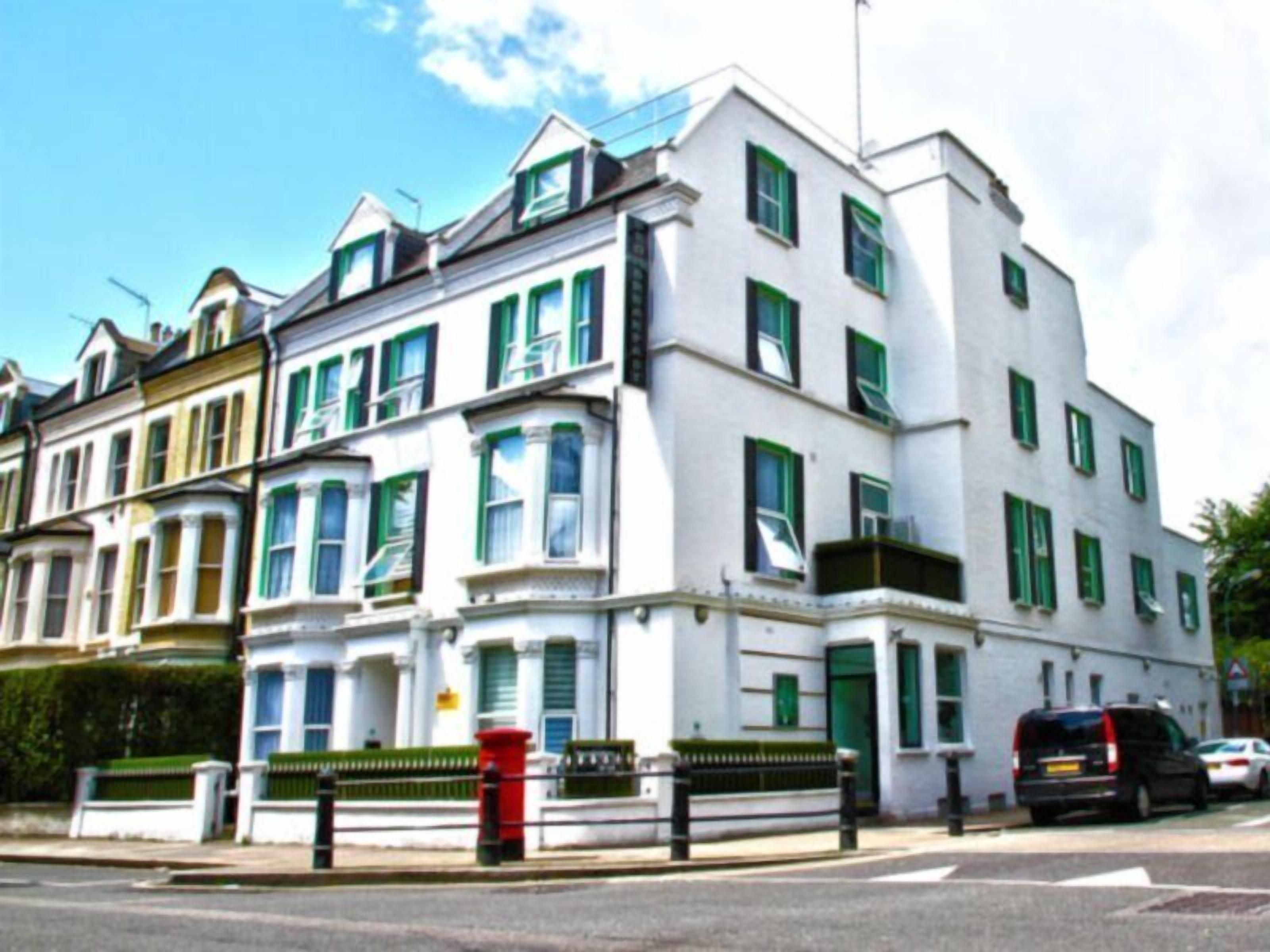 A row of white terraced houses with green window frames and a red post box.