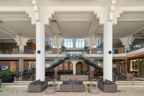 Un hall d’entrée spacieux avec un escalier central, des coins salon et un comptoir d’accueil.