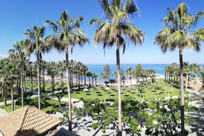 Un complexe hôtelier avec des palmiers, une plage et un ciel dégagé.