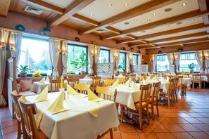 A restaurant with multiple tables and chairs, large windows, and a wooden ceiling. - Comfort Hotel Am Medienpark (Unterfoehring)