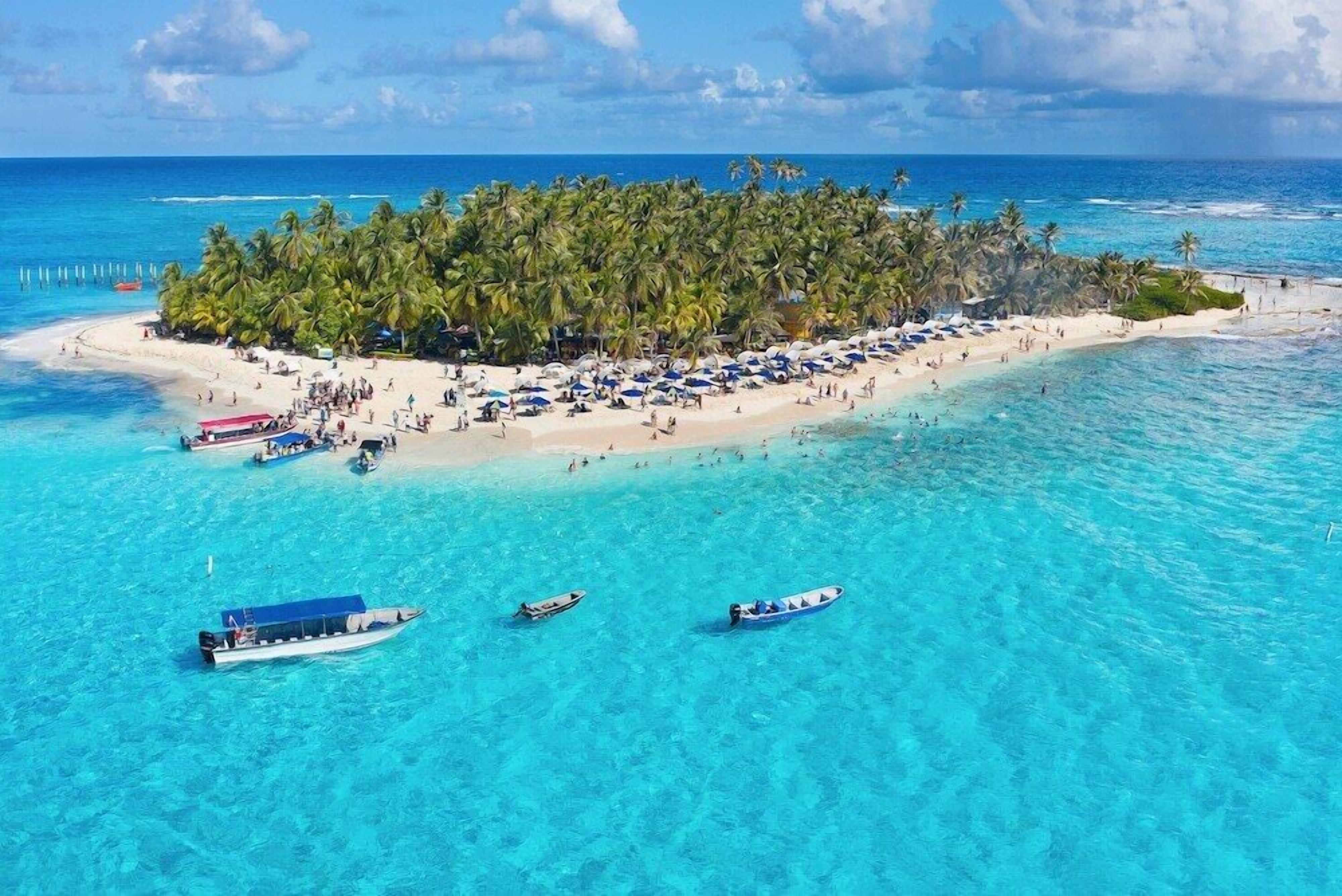 Tropisch eilandstrand met helder turquoise water, palmbomen en strandparasols.
