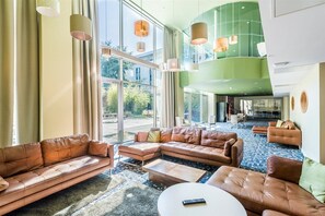 Un'ampia hall con divani in pelle, un tavolino da caffè e illuminazione a sospensione.