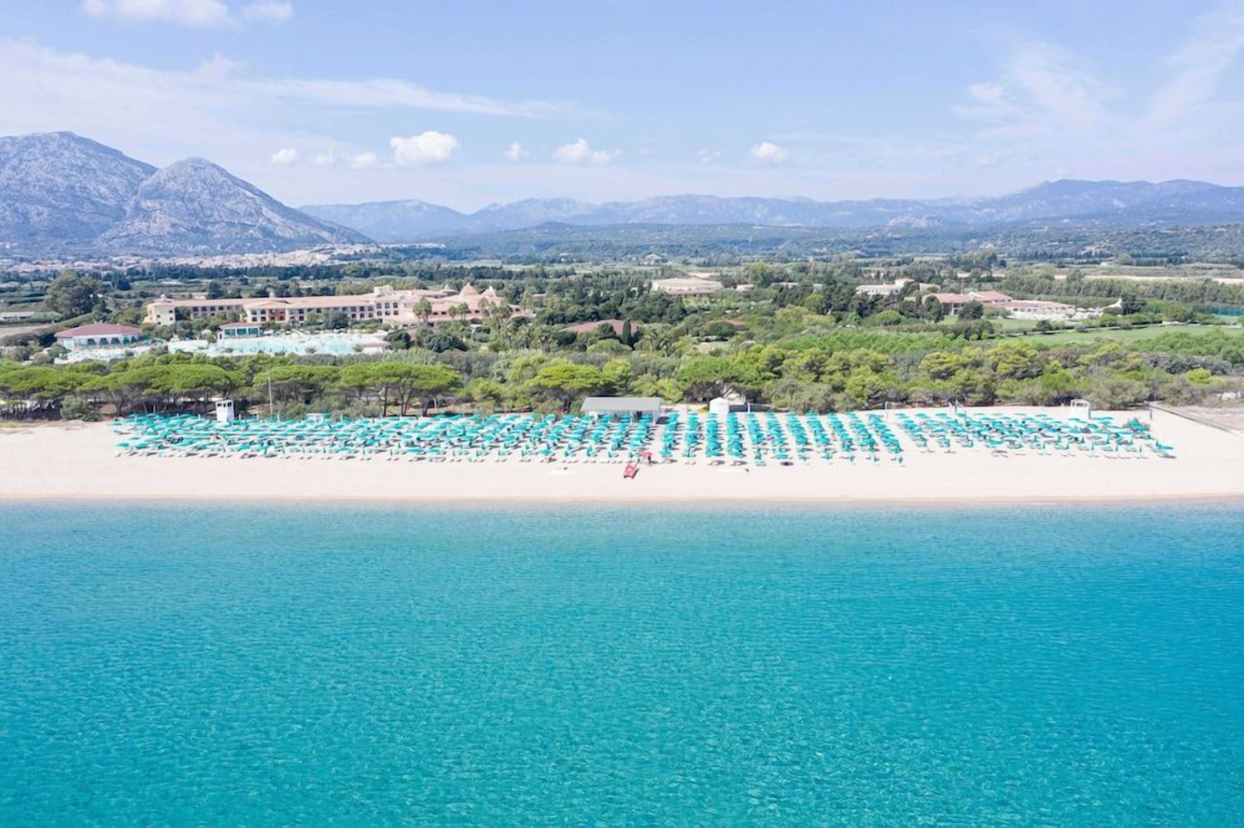 A beach with rows of umbrellas and a building in the background.