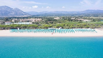 A beach with rows of umbrellas and a building in the background.