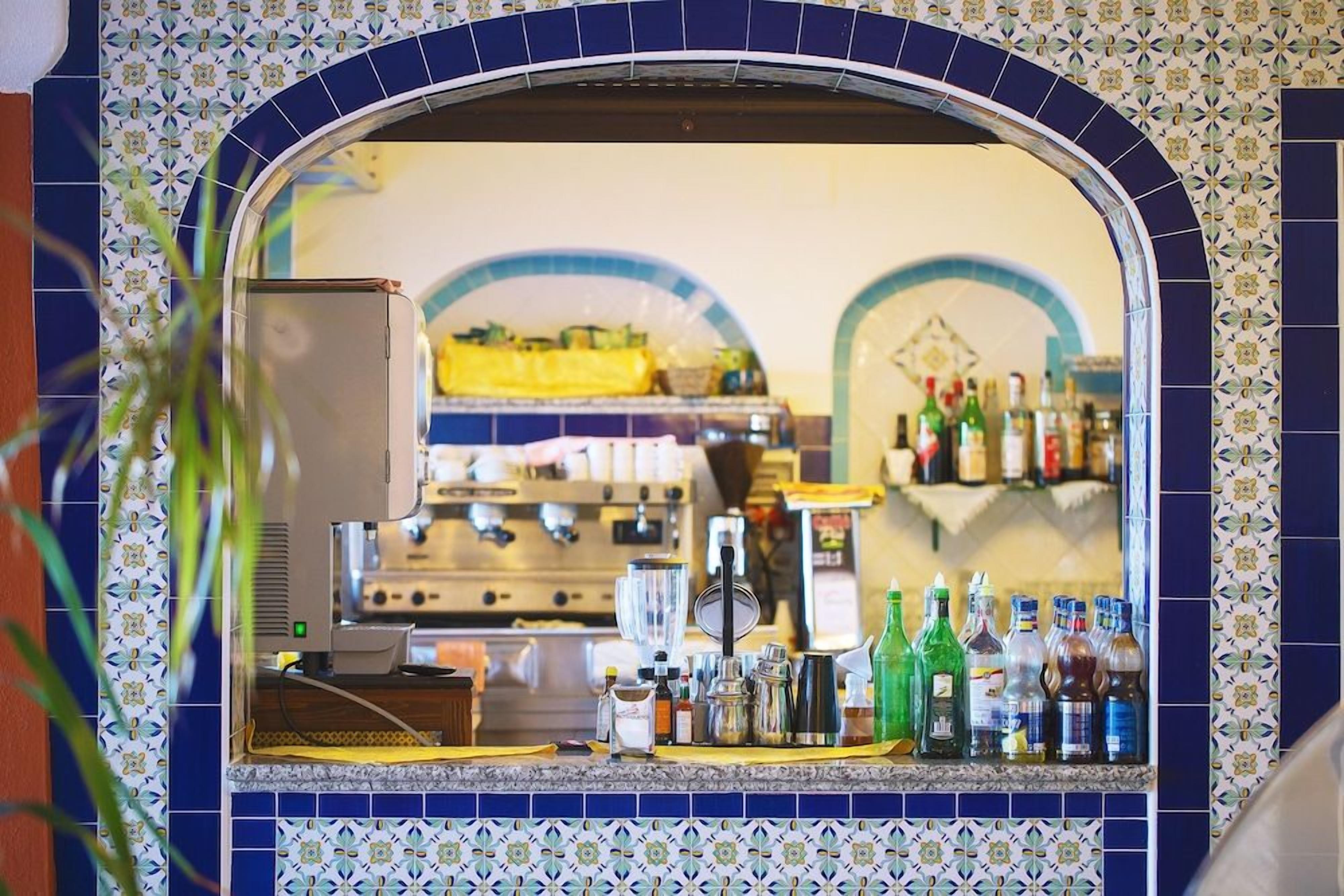 A bar area with a tiled backsplash and a mirror reflecting the interior.