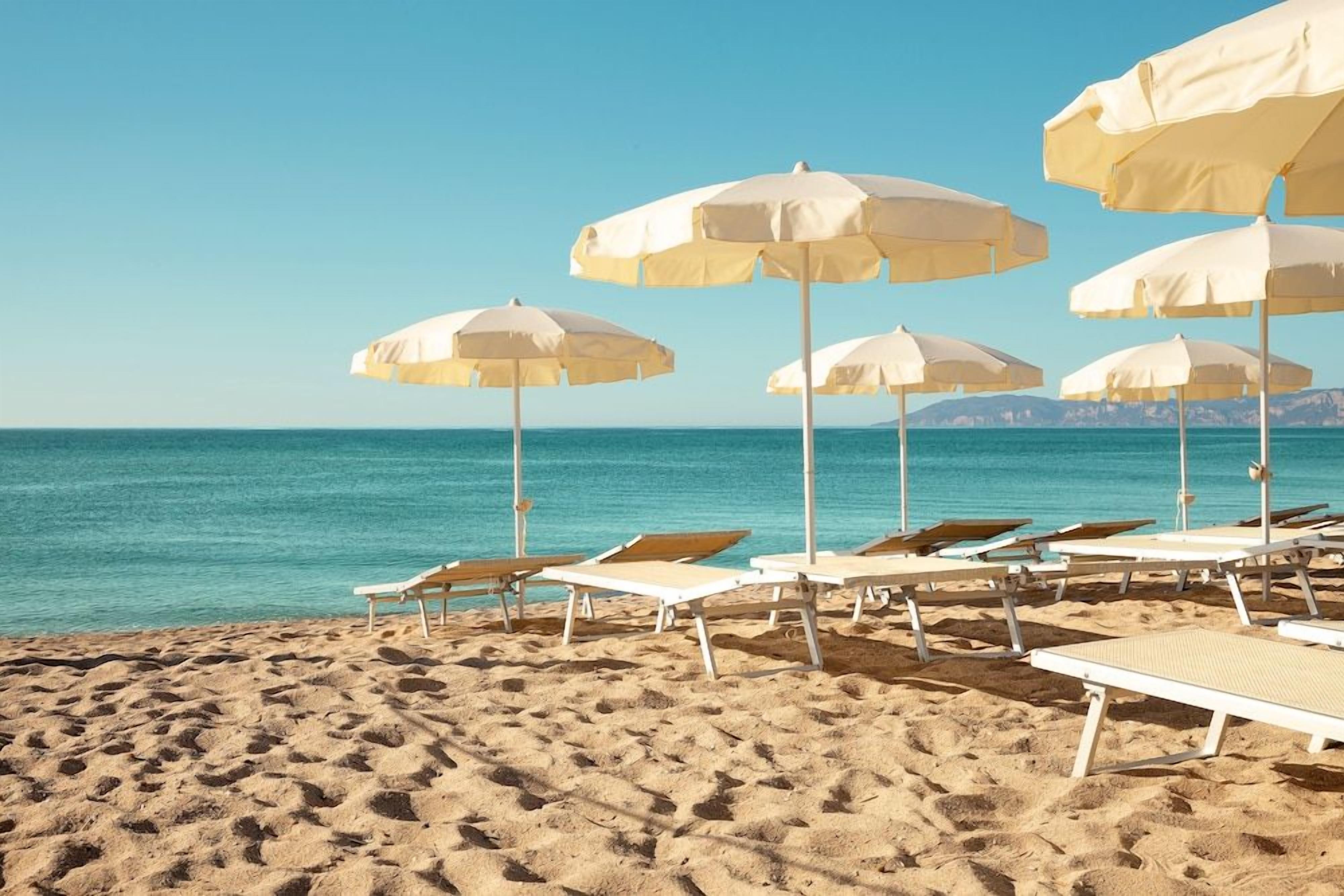 A beach with rows of sun loungers and umbrellas.