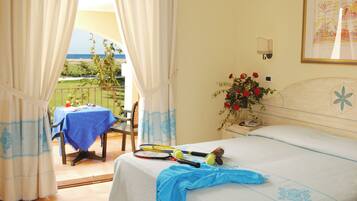 A bedroom with a bed, a table with a blue tablecloth, and a view of the outdoors.