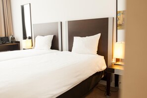 Una camera d'albergo con un letto grande, due comodini, uno specchio e una lampada.
