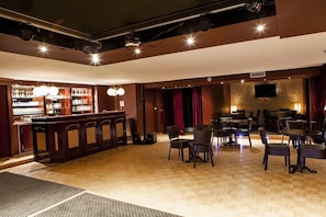A bar area with a counter, chairs, and a television screen. - Hotel Progress (Brussels)