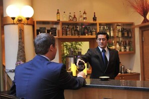 Eine Bar mit einer Theke, einem Mann, der ein Getränk einschenkt, und Regalen mit Flaschen.