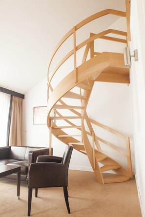 Eine moderne Inneneinrichtung mit einer Wendeltreppe, einem Sofa und einem Sessel.