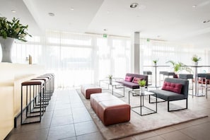 Una moderna hall d'hotel con una fila di sgabelli da bar, un divano e un tavolino da caffè.
