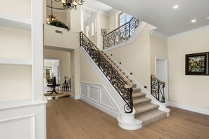 Eine prächtige Treppe mit aufwendiger Geländerarbeit, einem glatten Holzboden und einer Kristallleuchtre.