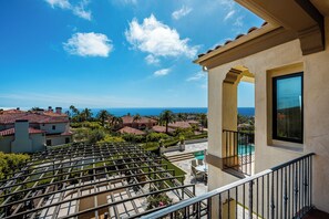 Ein Balkon mit Blick auf das Meer, ein Pool und ein Gebäude mit einem Ziegeldach.