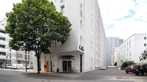 A modern building with a large tree in front, a sign for 'BW Hotel,' and several parked cars. - Premier Inn Berlin City Spittelmarkt (Berlin)
